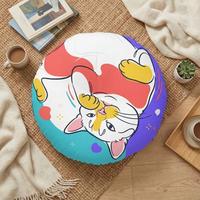 Round pink and yellow cat-themed tufted floor pillow featuring a cropped belly-up line-art cat; lifestyle setting showing a cozy corner, emphasizing warmth and playfulness