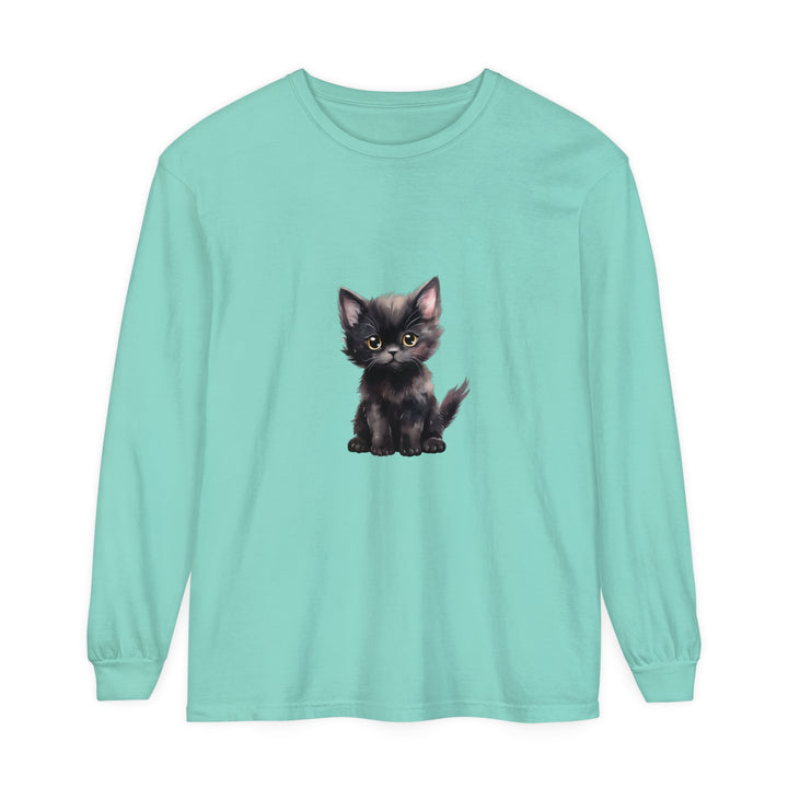 A cute black kitten with striking yellow eyes sits on a long sleeve t-shirt