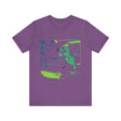 A black cat wearing a neon green T-shirt jumps away in fear from a cucumber silhouette on the ground