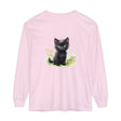 A cute black kitten stands in a vibrant flower garden on a long sleeve t-shirt