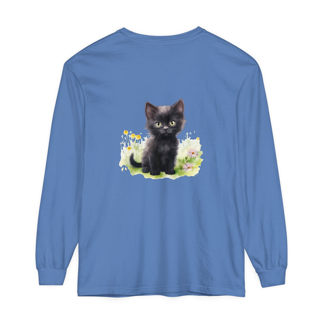 A cute black kitten playing in a colorful flower garden on a long sleeve t-shirt