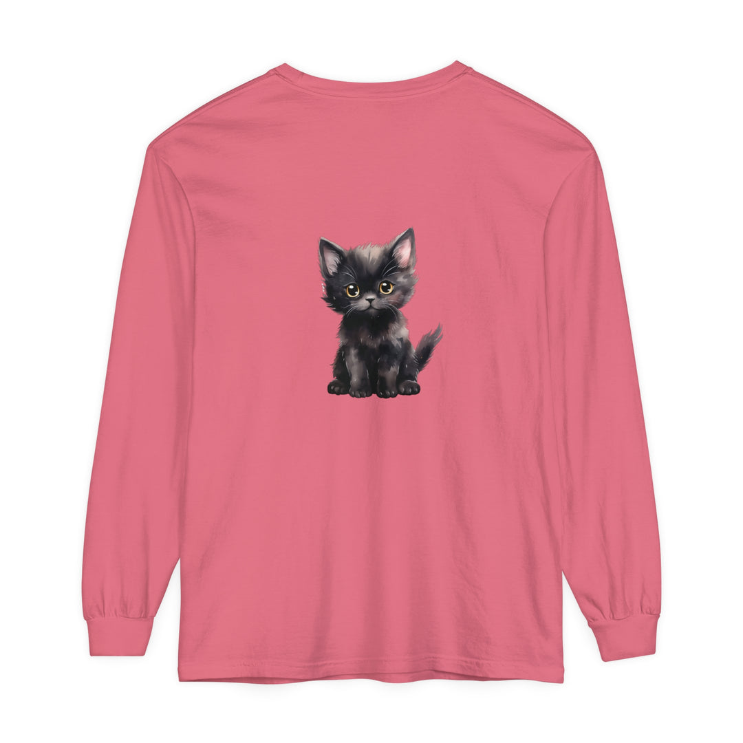 A black kitten with striking yellow eyes sits on a long sleeve t-shirt