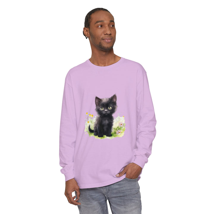 A cute black kitten playing in a colorful flower garden on a long sleeve t-shirt