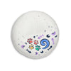 A round white tufted floor cushion with colorful printed graphics including paw prints, fish bones, crescent moons, and a blue swirl pattern, shown on a plain white background.