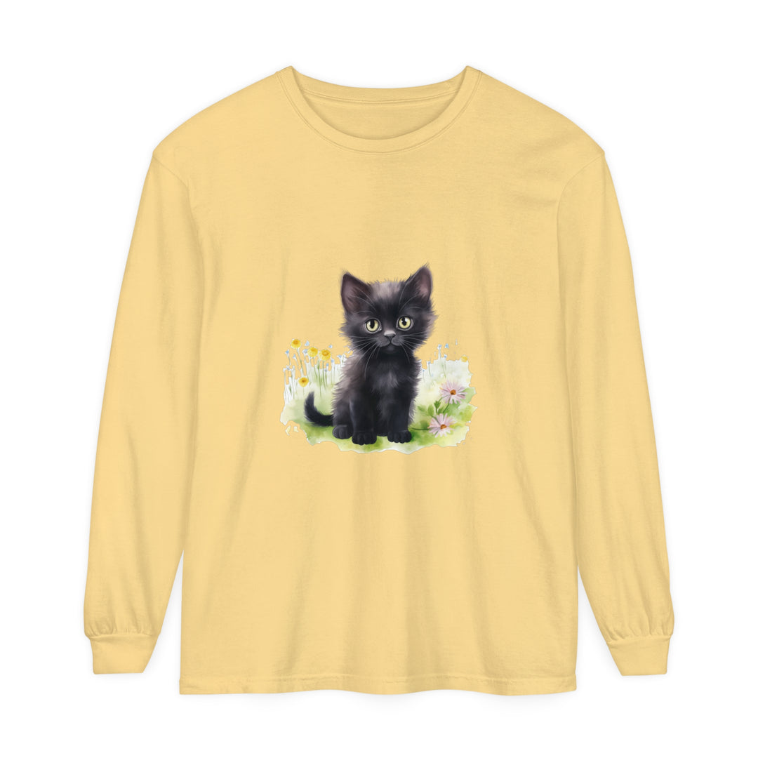 A cute black kitten with bright green eyes sitting among colorful flowers on a long sleeve t-shirt