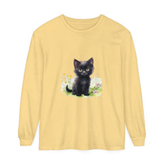 A cute black kitten with bright green eyes sitting among colorful flowers on a long sleeve t-shirt