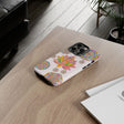 A light pink phone case with a mandala design featuring a delicate lotus flower