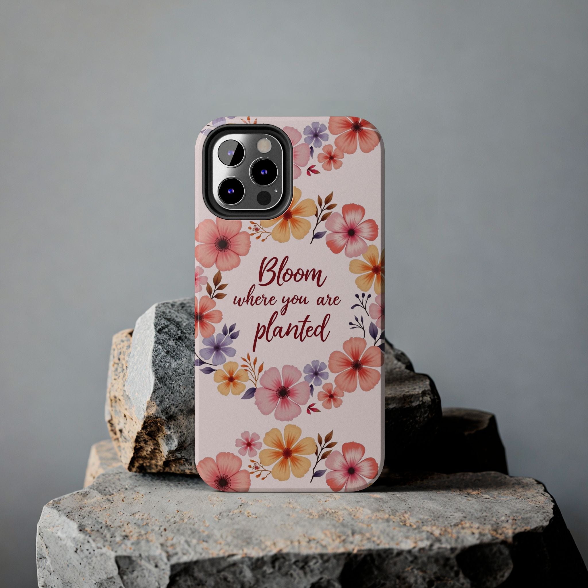 A light pink phone case with a flower garland design, illustrating the message bloom where you are planted