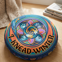 Close-up of a round tufted floor pillow featuring a blue-purple winter sacred-geometry cat with vibrant geometric rings; lifestyle setting for cozy, playful moments
