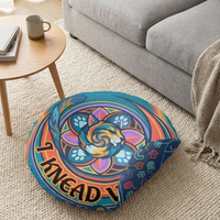 Lifestyle shot of a round floor pillow with a blue-dominant winter sacred-geometry cat design, featuring a curled cat motif, geometric rings, and vibrant colors in a cozy living room setting.