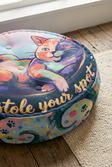 Close-up view of a round tufted floor pillow with a winter Cozy Cat design in deep navy, mint, coral, and gold highlights; lifestyle setting showing a cozy home corner with soft lighting (oil painting style).