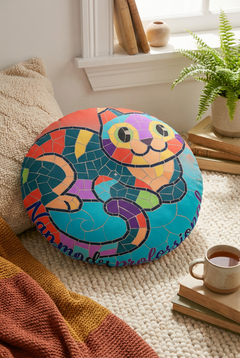 Round floor pillow featuring a bright mosaic cat in coral, teal, and yellow tones; lifestyle shot showing a cozy living space with the square-pattern cat motif on a plush seat.