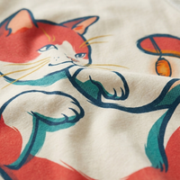 Pinkish-red Crescent Nap Cat tee in a cozy Ukiyo-e warmth palette (#E63946) displayed in a lifestyle studio shot with a relaxed, half-closed-eyed cat design and minimal flat-outline details.