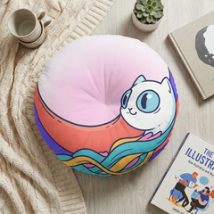 Round floor pillow in Surreal Cute Cat Dream design with bright colors (pink, yellow, turquoise, purple) showing a crescent cat, flowing ribbons, and floating paw in a lifestyle setting on a living room floor, close-up of tufted texture.