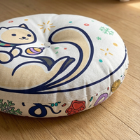 Round tufted floor pillow with Cozy New Year / Winter 2025 cat design in teal (#0EC3C9) and warm accents, shown in a cozy living-room close-up, featuring line-art cat in a crescent pose among confetti and stars, lifestyle setting.