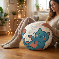 Round boho winter cozy cat floor pillow featuring a curled cat illustration in pink and peach tones, lifestyle shot in a cozy living room setting with festive accents.