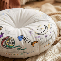 Close-up lifestyle shot of a round tufted floor pillow with bright blue and warm colors, featuring a cute cropped cat line-art in a winter cozy vibe, ideal for a cozy living space. The setting emphasizes comfort and everyday use.