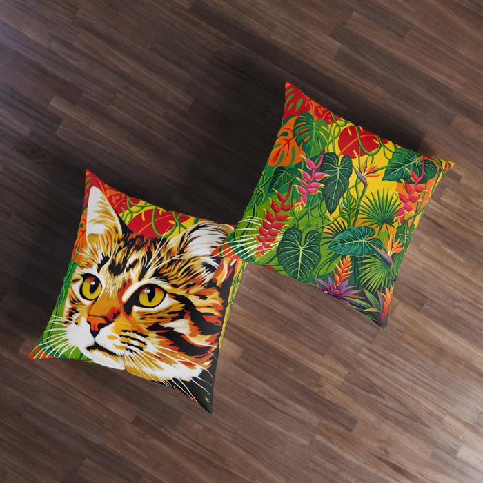 Two colorful pillows on a wooden floor, one with a cat design and the other with a tropical leaf pattern.